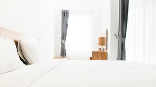 Quarto de hotel moderno com uma cama grande, uma mesa de cabeceira de madeira, uma pequena mesa e um guarda-roupa.