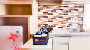 A kitchen with a Sharp refrigerator, a travelio complimentary food and beverage box, and a tiled backsplash. - Modern Furnished Studio Room Cinere Bellevue Suites Apartment (Depok)