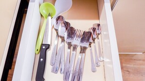 A drawer containing various utensils including forks, spoons, and a knife. - Modern Furnished Studio Room Cinere Bellevue Suites Apartment (Depok)