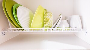 A white shelf with neatly stacked plates and bowls. - Brand New Studio Room Cinere Bellevue Suites Apartment (Depok)