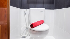 A white toilet with a red towel, a shower head, and a black and white tiled wall. - Brand New Studio Room Cinere Bellevue Suites Apartment (Depok)