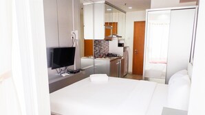 A modern hotel room with a large bed, a TV, a kitchenette, and a wardrobe. - Brand New Studio Room Cinere Bellevue Suites Apartment (Depok)