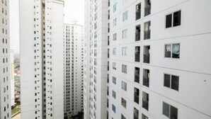 A high-rise residential building with multiple floors, featuring a uniform exterior facade and numerous windows. - 1BR with Sofa Bed at Bassura City Apartment (Jakarta)