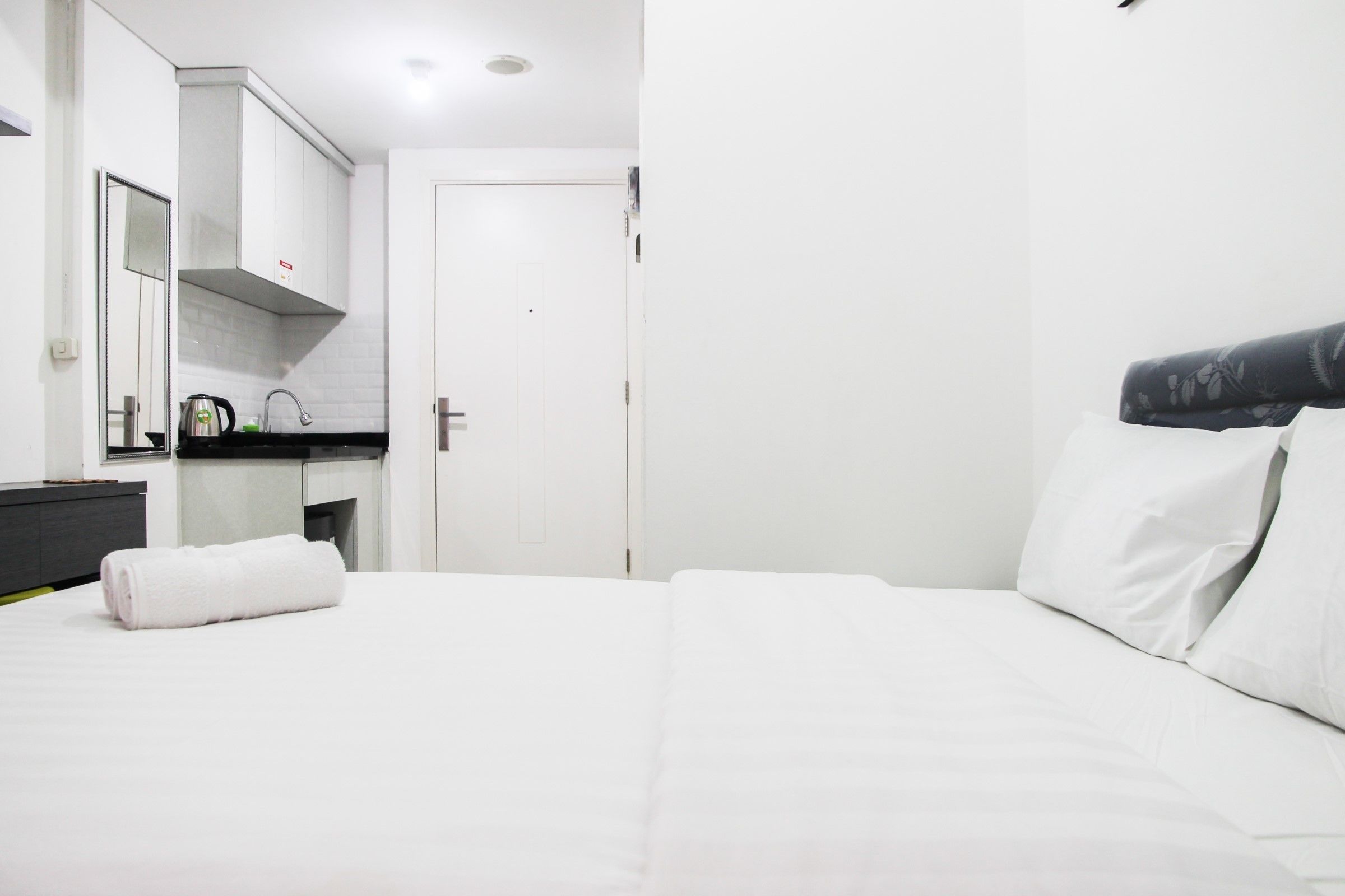 Une chambre d’hôtel avec un lit, une serviette blanche, un lavabo et un miroir.