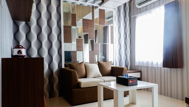 A modern living room with a sofa, a coffee table, and a TV. - Cozy 2BR Apartment with City View at Pavilion Permata (Surabaya)