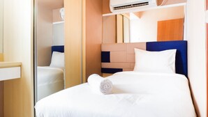 A hotel room with a bed, a mirror, a wardrobe, and an air conditioning unit. - Cozy 2BR Apartment with City View at Pavilion Permata (Surabaya)