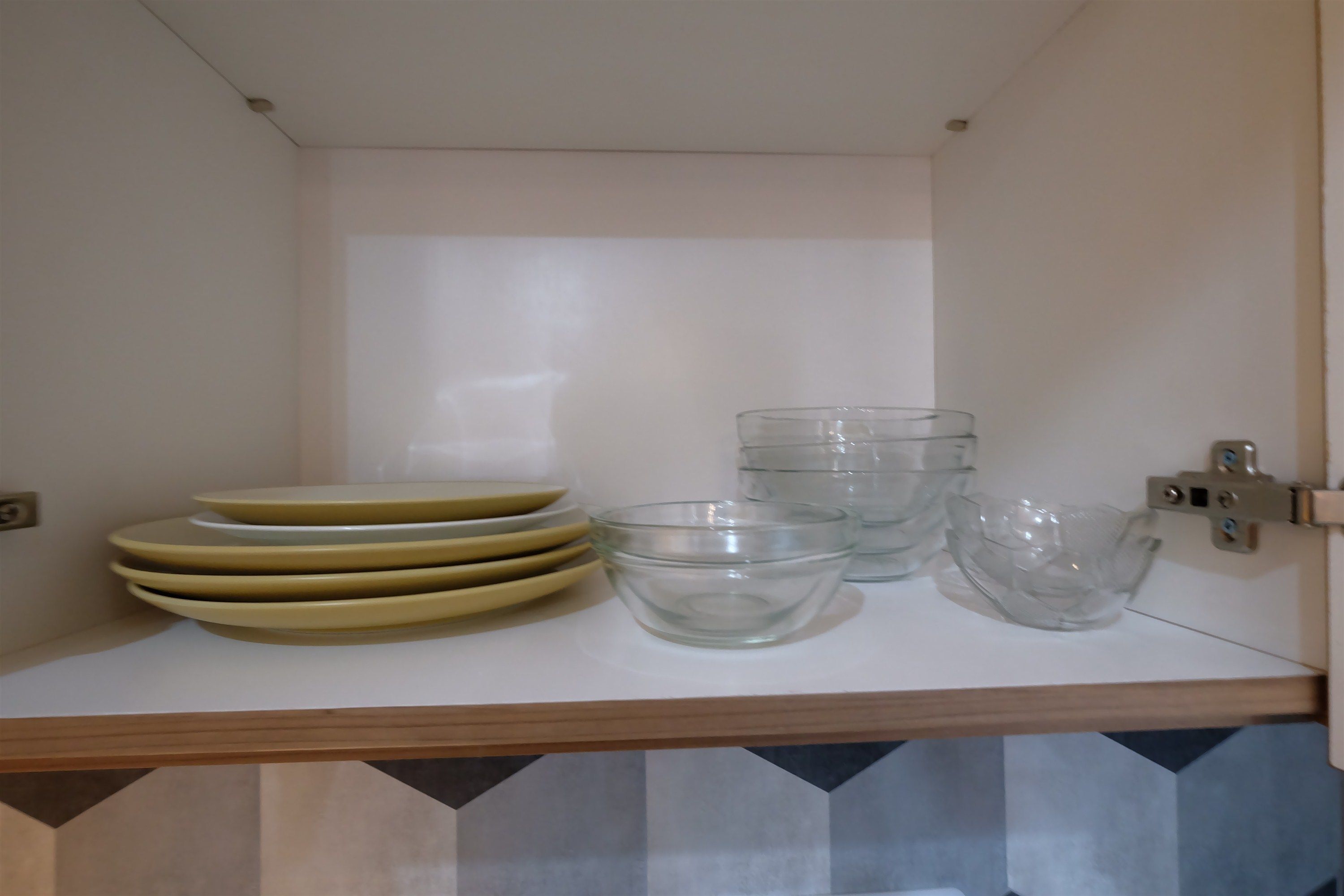 Un comptoir de cuisine avec une pile d’assiettes et des bols en verre transparent.