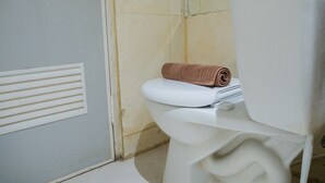 Casa de banho com sanita, toalha e ventilação.