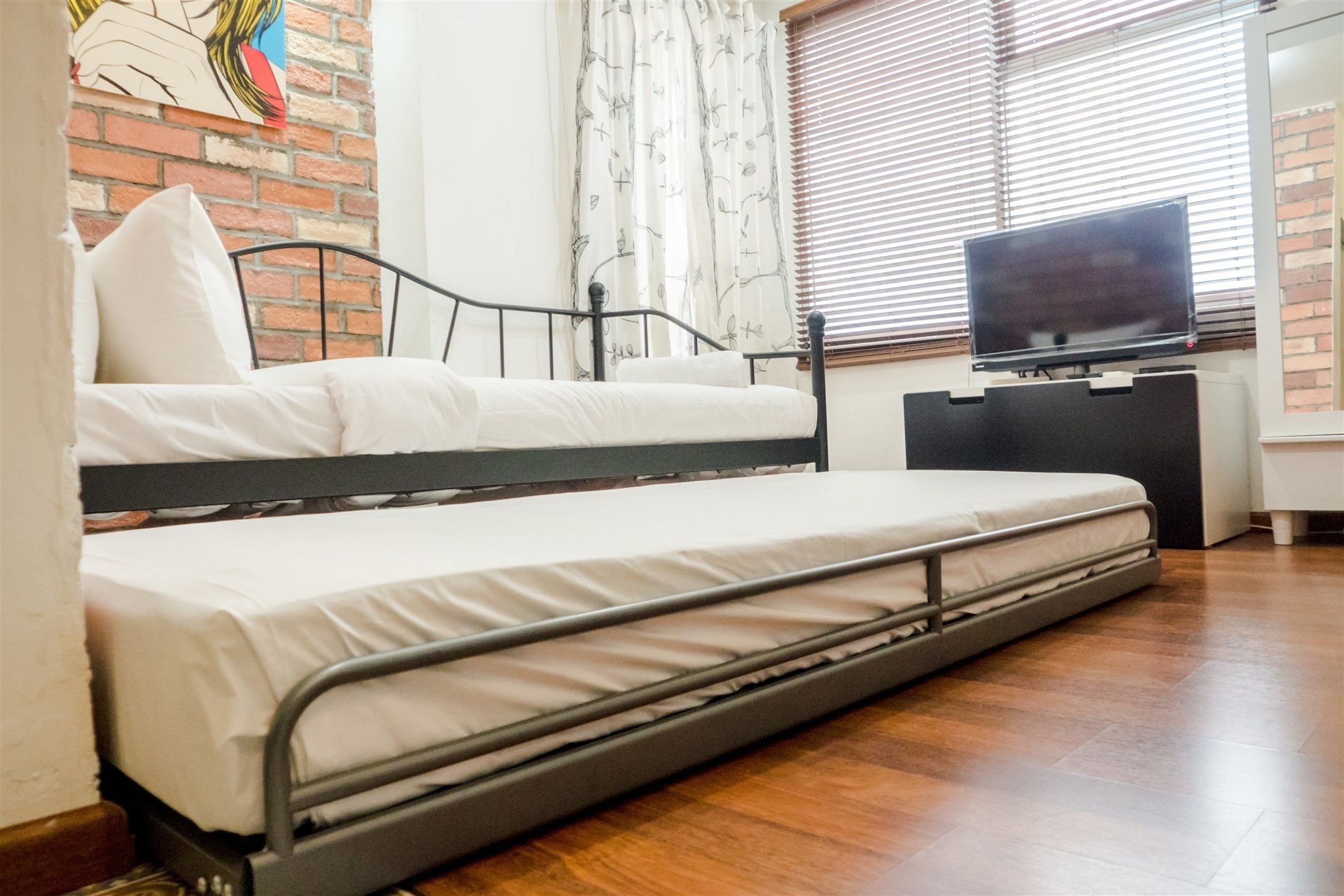 Une chambre avec un lit superposé, un téléviseur à écran plat posé sur un meuble et un mur en briques.