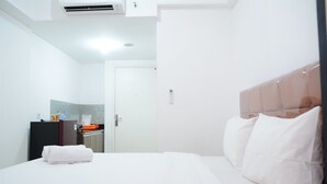 A hotel room with a bed, a desk, and a bathroom. - Comfy Studio Poris 88 Apartment (Tangerang)