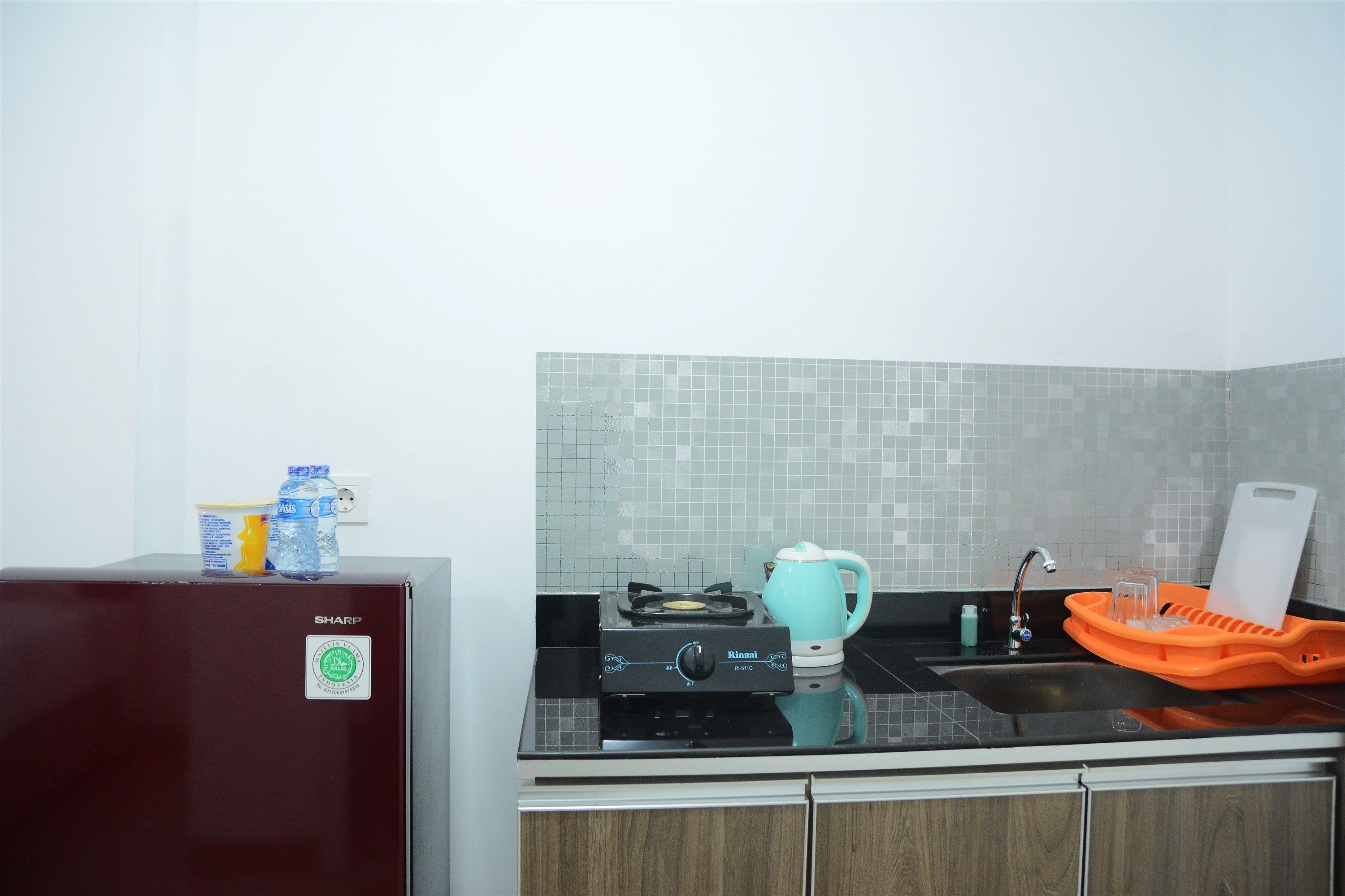 A kitchen with a refrigerator, stove, sink, and tiled backsplash.