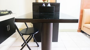 A compact dining area with a black table, a black chair, and a small cabinet with a water dispenser. - 2BR Mediterania Palace Kemayoran Apartment (Jakarta)