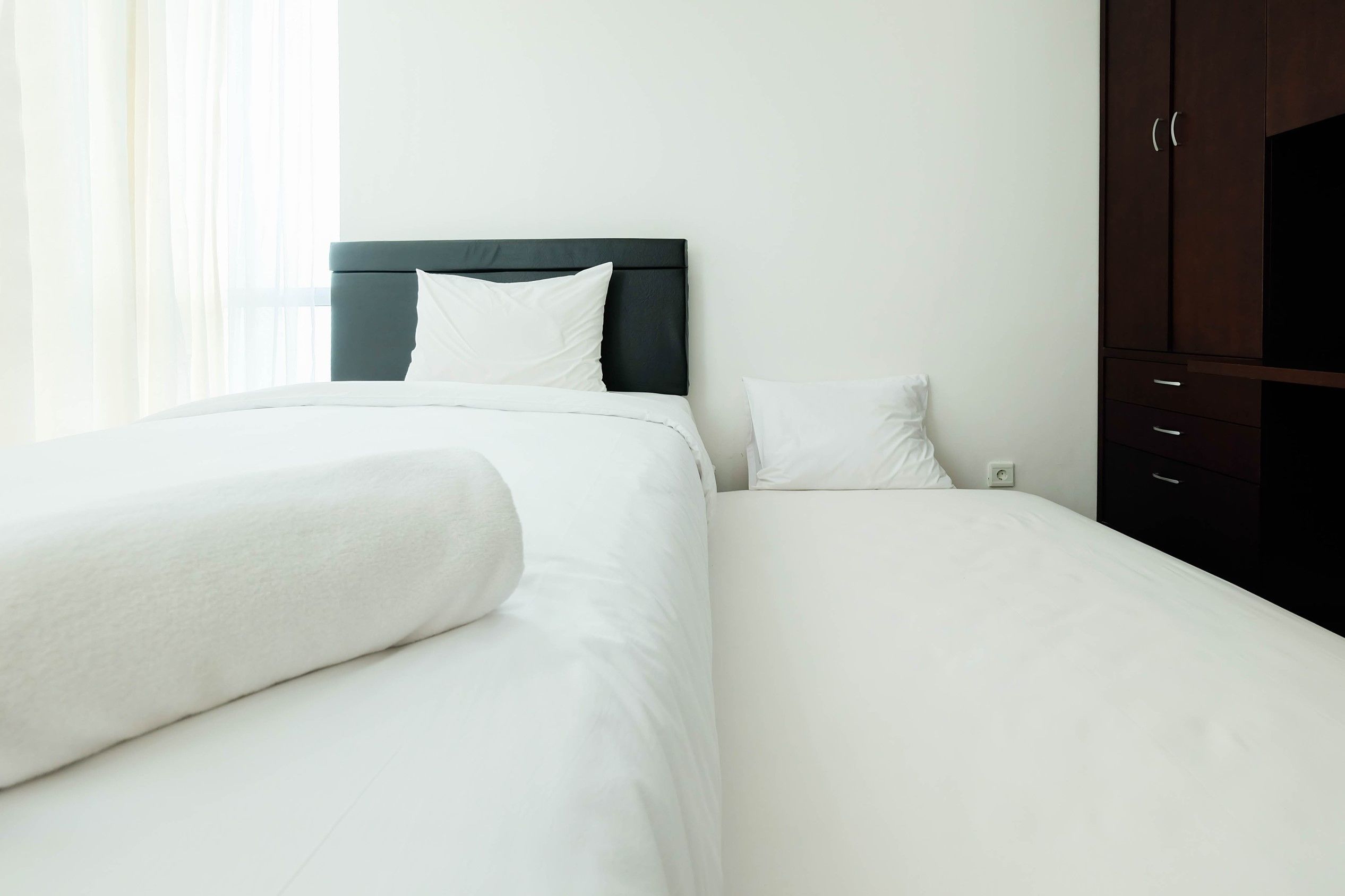 Una habitación de hotel con una cama, una mesita de noche y un armario.