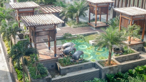A rooftop garden with wooden pergolas, a central water feature, and surrounding greenery. - Luxurious Furnished 2BR Kemang Village Apartment (Jakarta)