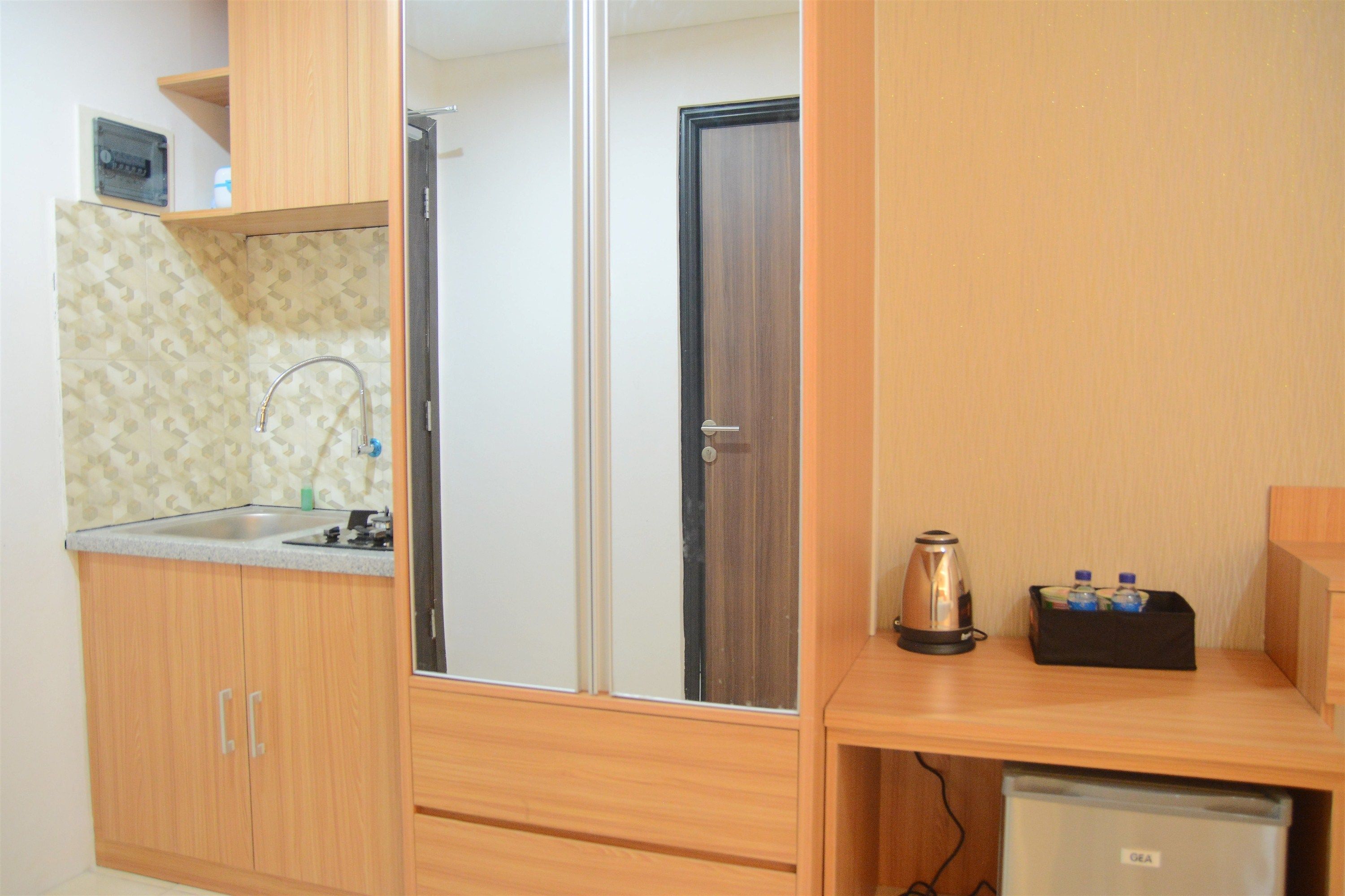 A compact kitchen with wooden cabinets, a sink, and a coffee maker on a small table.