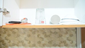 A shelf with a glass bottle, a white plate, and a black object. - Simply Studio Room @ Annora Living Apartement Tangerang (Tangerang)
