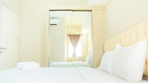 A hotel room with a bed, a wardrobe, and a window with curtains. - Comfortable 2BR Springlake Summarecon Apartment (Bekasi)