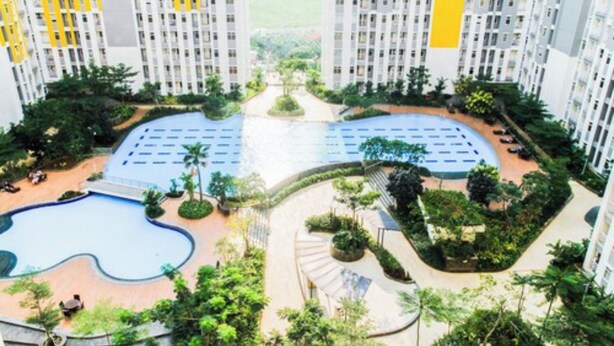 A high-rise residential building with a central swimming pool, surrounded by greenery and a landscaped area. - Comfortable 2BR Springlake Summarecon Apartment (Bekasi)