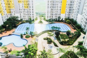 A high-rise residential building with a central swimming pool, surrounded by greenery and a landscaped area. - Comfortable 2BR Springlake Summarecon Apartment (Bekasi)