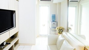 A modern living room with a flat-screen TV, a white sofa, and a water dispenser. - Comfortable 2BR Springlake Summarecon Apartment (Bekasi)