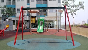 A playground with a swing set, slide, and climbing structure. - Homey Studio Room The Nest Apartment (Tangerang)