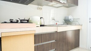 A modern kitchen with a countertop, stove, sink, and dish rack. - Comfortable 2BR Parahyangan Residence Apartment (Bandung)