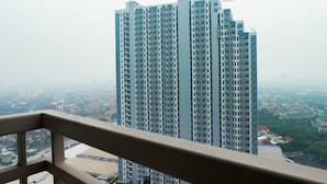 Un immeuble de grande hauteur, doté de nombreux étages, avec une grue de construction au sommet, et offrant une vue sur les bâtiments et la végétation environnants.