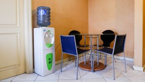 Un rincón de una habitación con un dispensador de agua, dos sillas y una mesa.