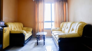 Una sala de estar con dos sofás de cuero amarillo, una mesa de centro de vidrio y un mueble pequeño.