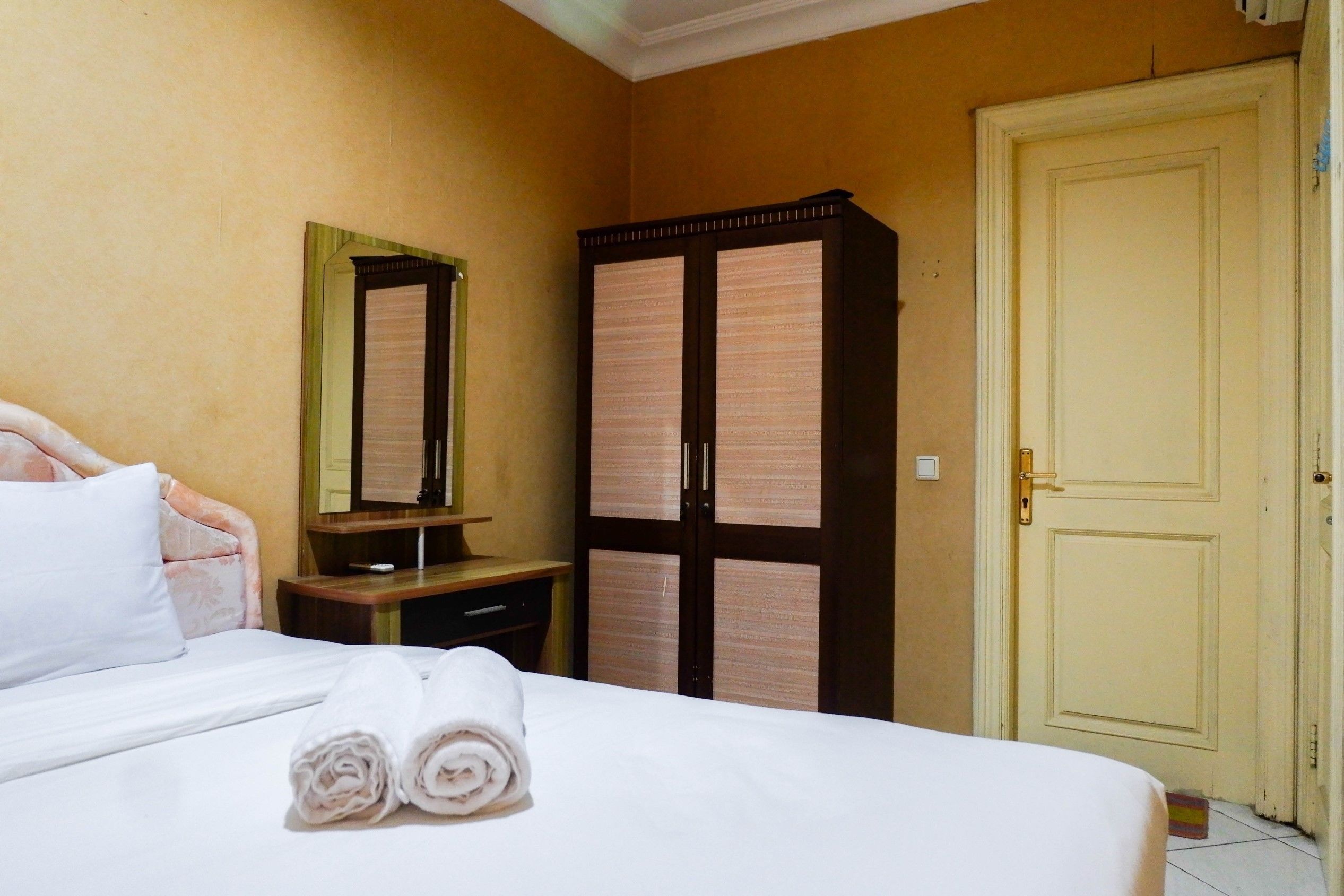 A hotel room with a bed, a wardrobe, a mirror, and a door.