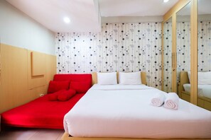 Una camera d'albergo con un letto, un divano rosso e un grande specchio.