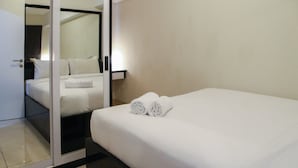Una camera d'albergo con un letto, uno specchio e una porta.