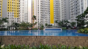 Una piscina circondata da un muro in mattoni, con alti edifici residenziali sullo sfondo.