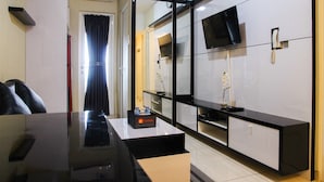 Una camera d'albergo moderna con una scrivania, una TV a schermo piatto montata a parete, un minibar e un armadio con ante scorrevoli.