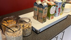 A breakfast buffet with various cereals, milk cartons, and yogurt containers on a counter.