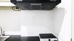Une cuisine avec une hotte noire, un évier et un plan de travail.