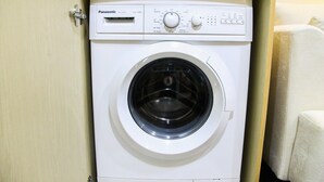 A white Panasonic washing machine in a wooden cabinet. - Modern Style The Oasis Studio Apartment with Comfortable Sofa (Cikarang)