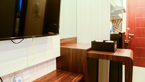 A kitchen with a wooden countertop, a television mounted on the wall, and a red door in the background.