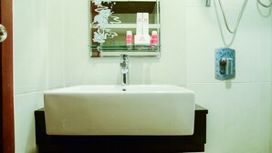 A bathroom with a white sink, a mirror above it, and a showerhead on the wall.