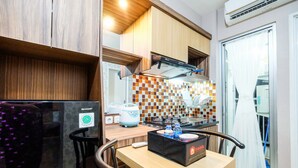 A compact kitchen with wooden cabinets, a built-in stove, and a tiled backsplash. - Classic 2BR Bassura City Apartment (Jakarta)