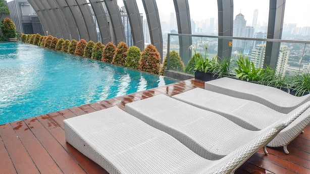 A rooftop pool area with lounge chairs and a view of the city skyline. - 2BR Cozy and Modern L'Avenue Apartment (Jakarta)