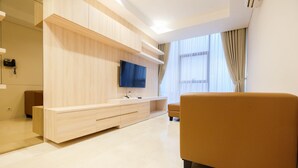A modern living room with a wooden entertainment unit, a flat-screen TV, and a sofa. - 2BR Cozy and Modern L'Avenue Apartment (Jakarta)