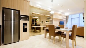 A modern kitchen with a stainless steel refrigerator, built-in microwave, and a dining area with a table and chairs. - 2BR Cozy and Modern L'Avenue Apartment (Jakarta)