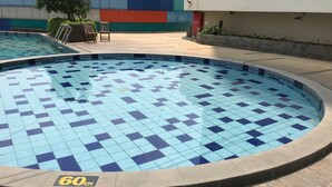 Una piscina circular con baldosas azules y blancas, rodeada por una terraza de madera.