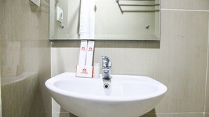 A bathroom sink with a mirror above it, a towel hanging on the wall, and two boxes of toiletries. - Pool View Studio Ara Residance Apartement Near Gading Serpong (Gading Serpong)