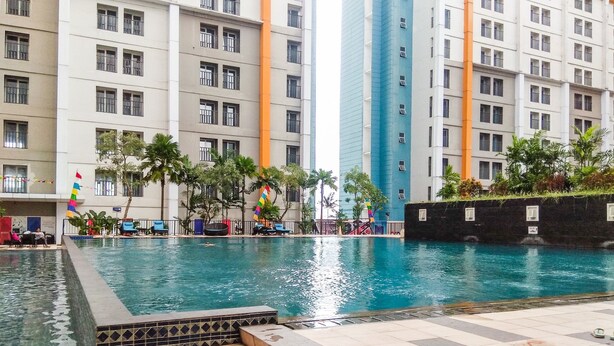 A swimming pool with tiled steps leading into it, surrounded by a building with multiple floors and balconies. - Pool View Studio Ara Residance Apartement Near Gading Serpong (Gading Serpong)