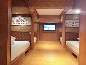 Una habitación pequeña con paneles de madera, dos camas, un televisor y decoraciones con diseños en las paredes.