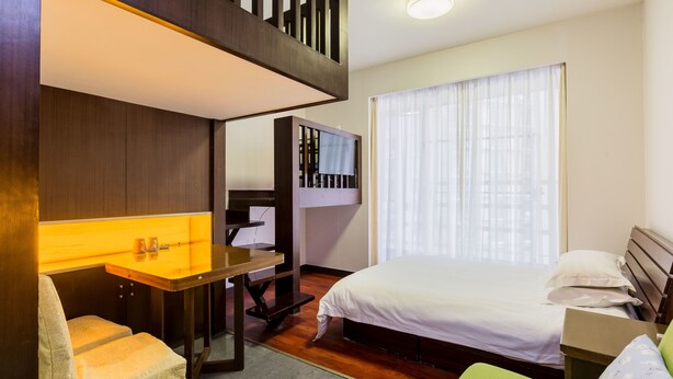 A compact hotel room with a bunk bed, a small desk with a chair, a bed with white bedding, and a large window with sheer curtains. - Shanghai Yueyi Apartment Hotel (Shanghai)