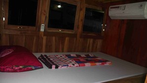 Una habitación de cabaña de madera con una cama, un almohadón rojo y un colcha.
