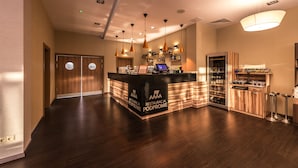 A modern hotel lobby with a reception desk, wooden cabinets, and pendant lighting.